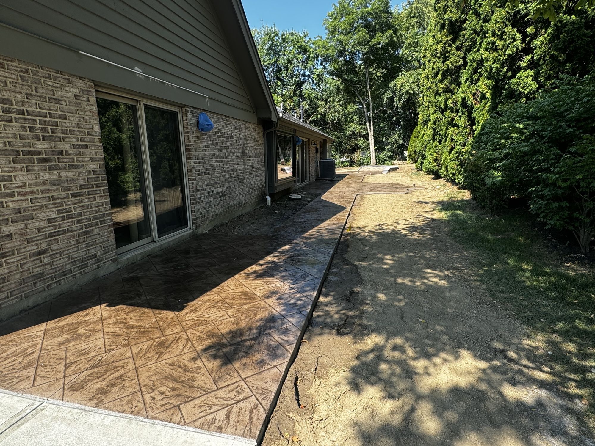 Stamped concrete patio and walkway along the back of a brick home